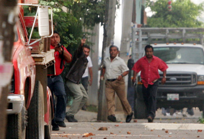 Raul Estrella, a photographer with El Universal, took these photos of gunmen, believed to be government agents, rushing toward protesters and journalists on the outskirts of Oaxaca on October 27, 2006. Brad Will, working near Estrella, was killed by gunfire that witnesses said appeared to have come from the direction of the gunmen. (El Universal/Raul Estrella)