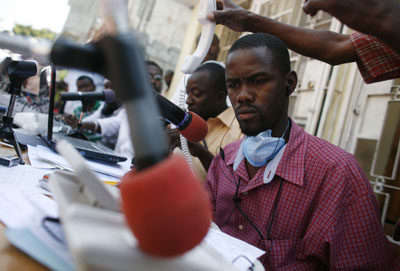 Outside their wrecked headquarters, Radio Caraibe's presenters broadcast from a makeshift studio in Port-au-Prince. (Reuters)