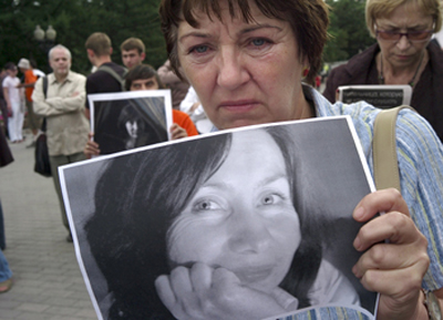 Скорбящая держит фотографию убитой журналистки Натальи Эстемировой. (AP)