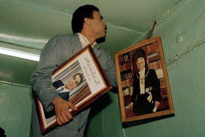 A barman in a coffeehouse in Tunis switches out the official photo of former Tunisian President Habib Bourguiba, right, to one of Zine El Abidine Ben Ali, after a bloodless coup in 1987. (AP/Laurent Rebours)