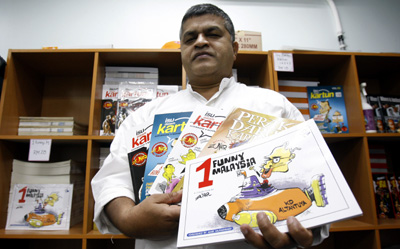 Zunar with copies of banned cartoon collections. (AP/Lai Seng Sin)