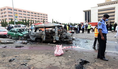 Nigerian police officer stands at scen of an exploded car bomb at Eagle Square in Abuja. (AP)