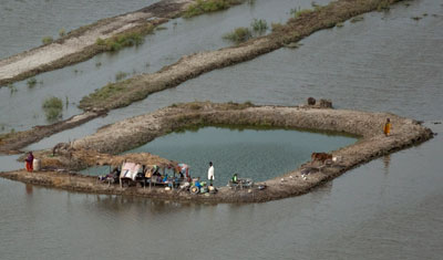 Pakistani residents stand on their property which is surrounded by flood waters in Sindh province. (AP)