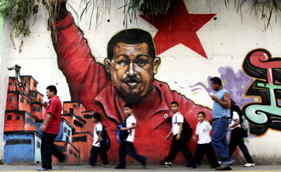 In Caracas, people pass by a mural of Chávez. (AP/Ariana Cubillos)