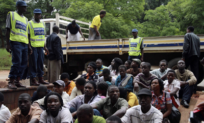 Men and women arrested for watching footage of the unrest in Egypt wait outside a Harare courthouse. (Reuters)