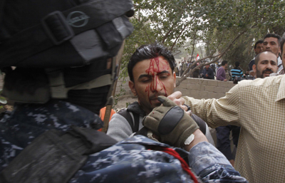An Iraqi officer hits Al-Alam cameraman Mohammed al-Rased during a demonstration in Basra today. (AP/Nabil al-Jurani)
