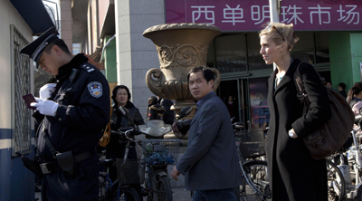 A Chinese policeman checks the identity of a foreign journalist, right, near the Xidan shopping district, a designated a demonstration site in an Internet call for protests in Beijing on Sunday. (AP)