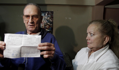 Maseda holds a document proving his release from prison next to his wife, Laura Pollán. (AP/Franklin Reyes)