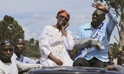Kizza Besigye and his wife, Winnie Byanyima, wave to supporters during the procession. (AP)