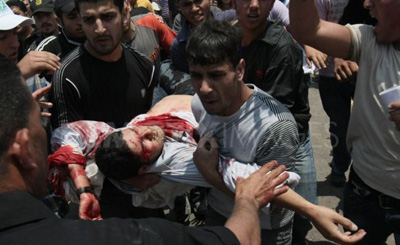Men carry wounded photojournalist Mohammed Othman. (Mazen al-Breem/Demotix)