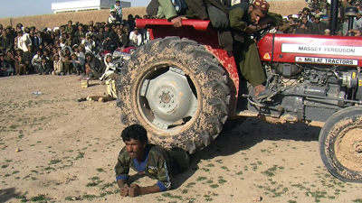 Khpalwak captured all aspects of life in Uruzgan, including local amusements like a man showing his ability to withstand the weight of this tractor. (Khpalwak)