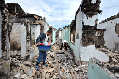 Ethnic Uzbek men look for their belongings at a destroyed house outside Osh on June 16, 2010. (AFP)