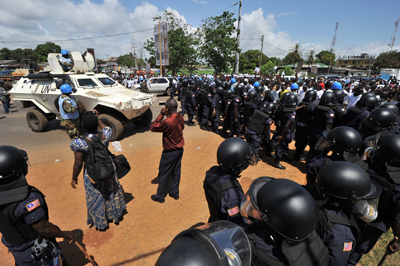 Liberian police face opposition CDC supporters in the run-up to presidential elections. Three broadcasters have been shut down by the government for covering the CDC party's campaign. (AFP)