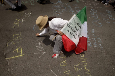Un manifestante se detiene a escribir un eslogan por la paz en una marcha contra la violencia en México en agosto. (AP)