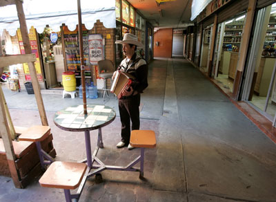 Javier Soto toca su acordeón mientras busca a turistas en un mercado vacío en el centro de Nuevo Laredo (26 de enero del 2006). (AP/Gregory Bull)
