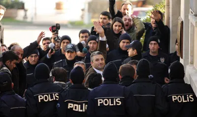 Behind a wall of police, Turkish writer Ahmet Şik arrives at a courthouse in Istanbul to face antistate charges. (Reuters)