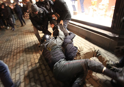 A police officer falls down as he tries to detain a demonstrator during protests against alleged vote rigging in Russia's parliamentary elections in Triumphal Square in Moscow Wednesday. (AP)