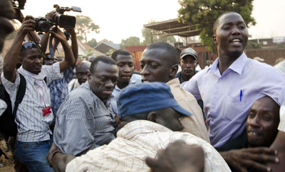 Ugandan opposition leader Kizza Besigye, second from left, is shielded by supporters Tuesday as security personnel try to detain him. Photojournalist Isaac Kasamani is at far left. (AFP/Michele Sibiloni)