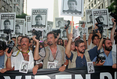 Fotógrafos levantan retratos de José Luis Cabezas durante una multitudinaria manifestación en Buenos Aires, el 25 de febrero de 1997, para protestar por el asesinato de Cabezas el mes anterior (AP/Daniel Muzio)
