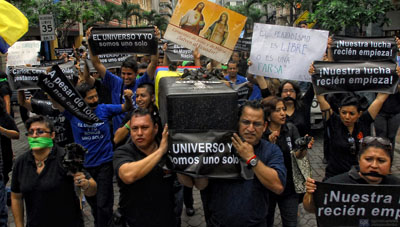 Personal de El Universo carga con un ataúd falso en protesta por la decisión de ratificar la sentencia contra los directivos del diario. (AFP/Camilo Pareja)