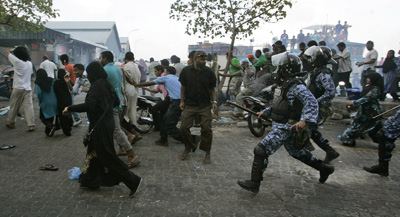 Police chase supporters of former President Mohamed Nasheed, who resigned on Tuesday. (AP/Sinan Hussain)