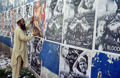 A Pakistani man removes movie posters on a cinema wall in Rawalpindi. (AFP/Abid Zia)