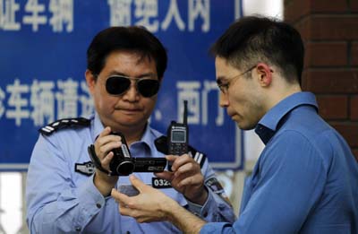 A police officer records the press card of a journalist outside a hospital where Chen Guangcheng is seeking treatment. (AP/Ng Han Guan)