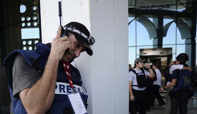 A journalist talks on his satellite phone outside the Rixos Hotel in Libya in August 2011. (AFP/Filippo Monteforte)