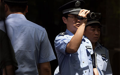 A police officer films members of the press gathered outside the Beijing hospital where Chinese activist Chen Guangcheng was staying on May 3. (AFP/Ed Jones)