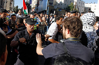 A member of the Palestinian security forces scuffles with a journalist in Ramallah Sunday. (Reuters/Mohamad Torokman)