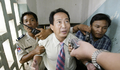 Radio journalist Mam Sonando, seen here with police in court in 2005, was charged with anti-state activities on Monday. (Reuters/Chor Sokunthea)