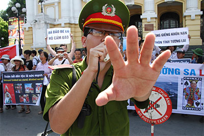 A police officer blocks photographers at an anti-China protest in front of Hanoi's Opera House on July 22. (Reuters/Nguyen Lan Thang)