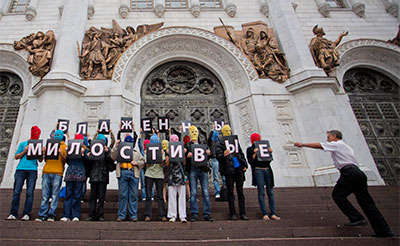 A security guard at the Christ the Saviour Cathedral, right, runs toward Pussy Riot supporters holding Cyrillic letters reading 'Blessed are the Merciful' in Moscow on Aug. 15. (AP/Novaya Gazeta, Yevgeny Feldman)