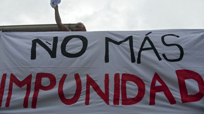 A woman stands next to a banner reading "No more impunity" in Colombia. (AFP/Raul Arboleda)