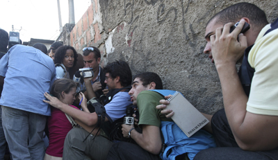 Journalists take cover in a shootout between police and drug traffickers in Brazil. (AP/Silvia Izquierdo)