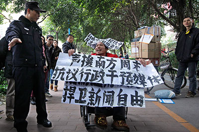 A supporter of Southern Weekly newspaper outside its headquarters in Guangzhou holds banners reading, 'Support Southern Weekly. Protest intervention in media. Defend press freedom.' (AP/Vincent Yu)