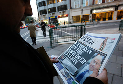 A man reads a newspaper article about Lord Justice Brian Leveson's report on media practices in central London November 29, 2012. (Reuters/Olivia Harris)