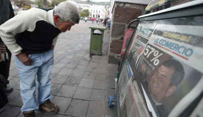 A passer-by stops to look at a newspaper the day after Correa is re-elected. (AFP/Rodrigo Buendia)