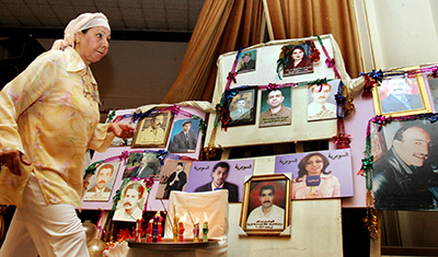 An Iraqi journalist walks past a wall of photos of journalists killed during the Iraq War. (AP/Samir Mizban)