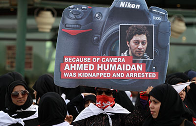 A Bahraini anti-government protester carries a sign with the picture of a jailed photographer during a march in Karranah, Bahrain, on Friday. (AP/Hasan Jamali)