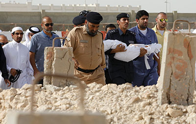 A civil defense officer carries the body of a young victim a mall fire during a funeral in Doha on May 29, 2012. Hearings to determine criminal responsibility for the fire are underway. (Reuters/Hamad I Mohammed)