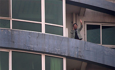 Tibetan blogger Woeser waves from the balcony of her home in Beijing on March 8. She was named an International Woman of Courage by U.S. Secretary of State John Kerry, but rather than being allowed to accept it, she was placed under house arrest. (Reuters/Petar Kujundzic)