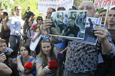 Journalists in Kiev protest police officers' failure to intervene in an assault against two reporters. A demonstrator holds a photo of a man said to have been among the assailants. (Reuters/Gleb Garanich)