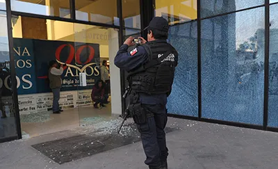 A Mexican police officer photographs the main entrance of El Siglo de Torreón after an attack on the offices. (AFP/El Siglo de Torreón)