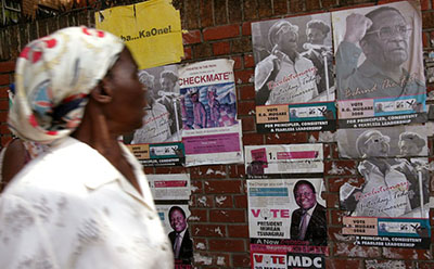 A Zimbabwean citizen passes election posters advertising election candidates. At least four journalists have been attacked in the lead-up to the elections in July. (AFP/Alexander Joe)