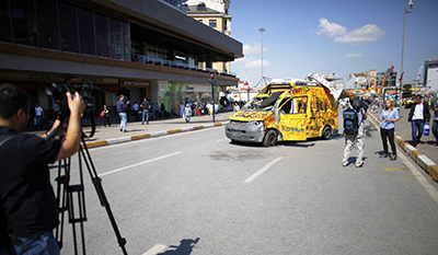 A TV crew films near a vandalized news vehicle in Taksim Square. (Reuters/Stoyan Nenov)