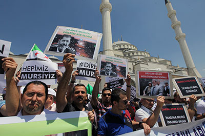 Turks hold posters reading "We are all Morsi" and "Resist, Morsi" outside Kocatepe Mosque in Ankara, Turkey, on July 5. (AP/Burhan Ozbilici)