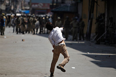 A Kashmiri youth throws a piece of brick at Indian police during a protest in Srinagar on July 18. Indian paramilitary soldiers fired at protesters in the region last week, killing four. (Reuters/Danish Ismail)