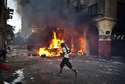 A man runs past a burning vehicle in Ramses Square. (AFP/Virginie Nguyen Hoang)