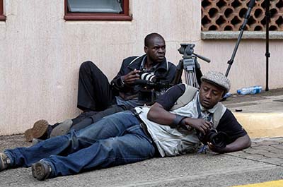 Two photographers take cover outside the Westgate Mall. (AP/Sayyid Azim)